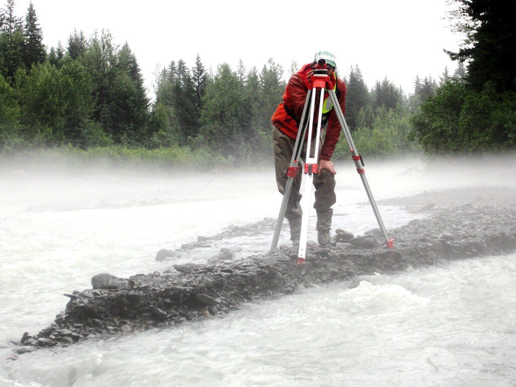 Surveyor with tripod in a river